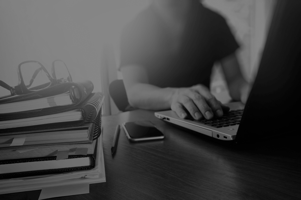 designer hand working with  digital tablet and laptop and notebook stack and eye glass on wooden desk in office-dark
